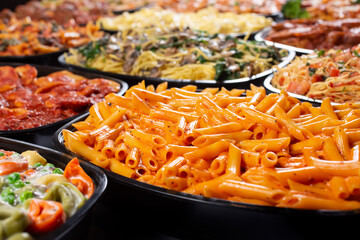A view of several pasta trays, featuring penne.