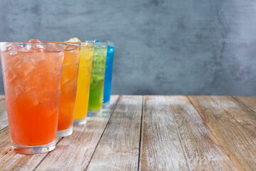 A view of several iced cold drinks with a rainbow motif, on the left side of the frame.