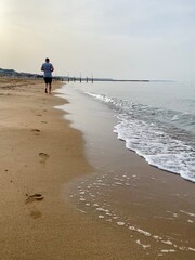 Jogging man on the beach barefoot