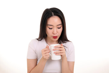 Beautiful young south east Asian woman holding white coffee tea cup emotion expression on white background look down blowing to coo - obrazy, fototapety, plakaty