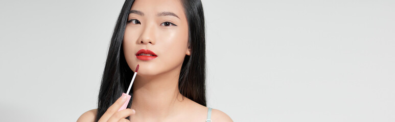 Attractive and beautiful Asian girl paint lips a pink lipstick, smiling make-up girl isolated on white background