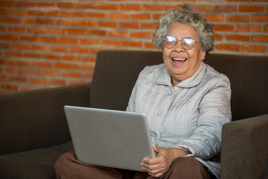 Portrait Of Aged Female Watching Zoom Video Meeting Online,Happy Middle Aged Senior Woman Sitting On Couch Holding Using Laptop Device During Video Call With Family Friends.