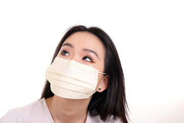 Beautiful young south east Asian woman wearing yellow off white three ply anti virus surgical face mask on white background look up