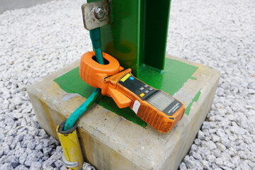 Earth resistance clamp meter during recheck electrical high voltage ground copper bar on steel structure.