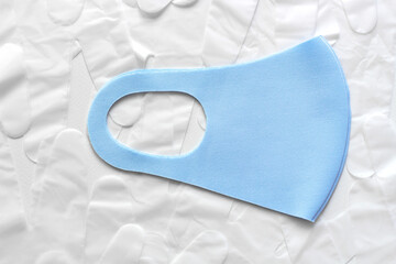 Protective blue face mask with white disposable vinyl gloves above white background. Infection prevention during lockdown.