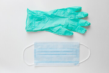 Pair of mint nitrile disposable gloves and sitgical face mask lie on white table. Safety first concept.