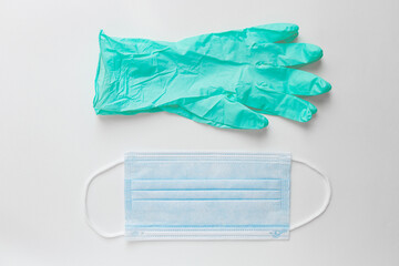 Fototapeta premium Pair of mint nitrile disposable gloves and sitgical face mask lie on white table. Safety first concept.
