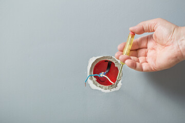 The electrician inserts a tester screwdriver into the hole of the socket to determine the phase wire