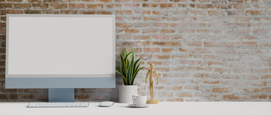 Computer with mock-up screen on white table with decorations, copy space and brick wall background, 3D rendering