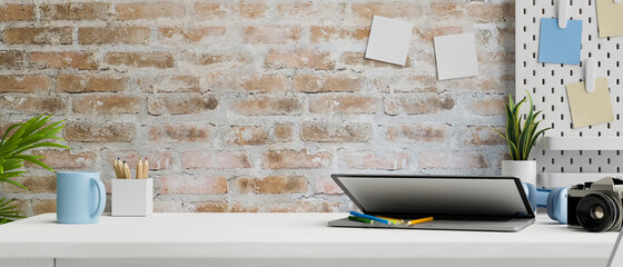 Contemporary working space with laptop, camera, stationery and supplies on table and brick wall, 3D rendering