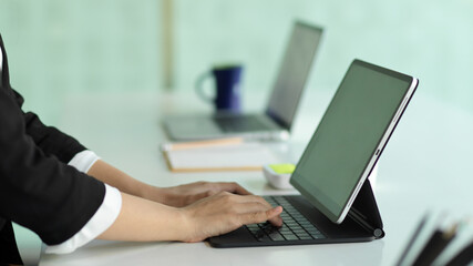Fototapeta na wymiar Side view of businesswoman hands typing on tablet keyboard