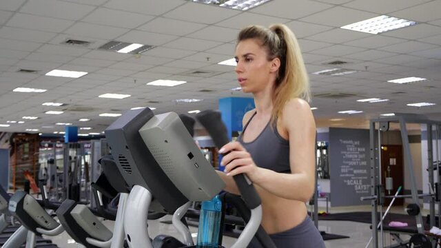 Young woman working out on orbi track at gym exercising
