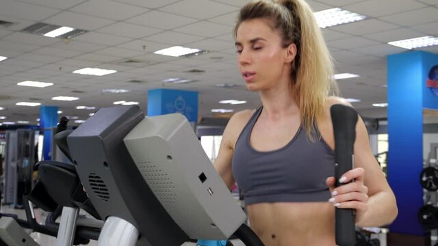 Young woman working out on orbi track at gym exercising