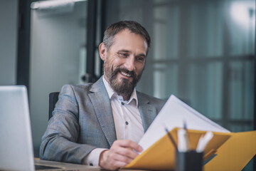 Fototapeta premium Happy business man looking at documents in folder