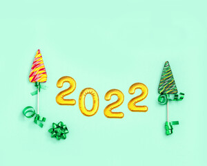 Obraz premium New year background with Lollipops as Christmas tree and metallic gold numeral 2022.