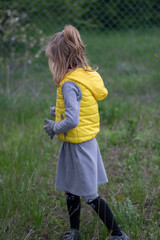 Kid girl walking by grass at backyard and wearing clothes of trendy color of the year 2021 - Illuminating Yellow and Ultimate Gray