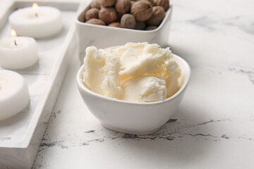 Bowl with shea butter on light background