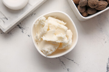 Bowl with shea butter on light background
