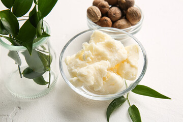 Bowls with shea butter and nuts on light background, closeup