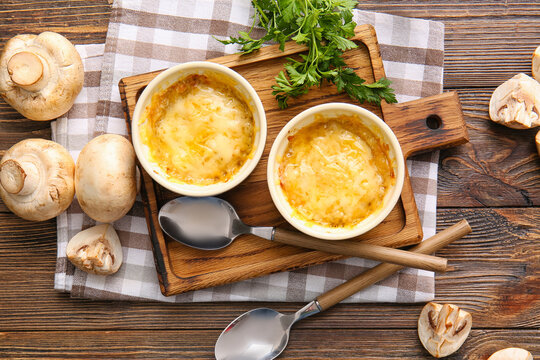 Ramekins with tasty julienne and ingredients on wooden background