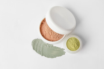 Jars with cosmetic clay on white background
