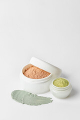 Jars with cosmetic clay on white background