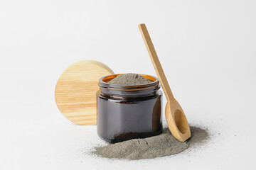 Jar and spoon with cosmetic clay on white background