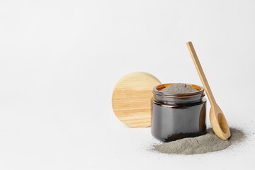 Jar and spoon with cosmetic clay on white background