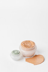 Jars with cosmetic clay on white background