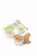 Jars with cosmetic clay on white background