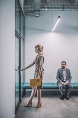 Woman entering office man sitting in corridor