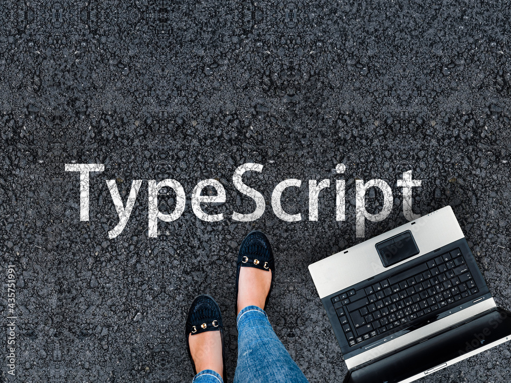 Fototapete typescript programming language. legs in sneakers standing next to laptop and word typescript