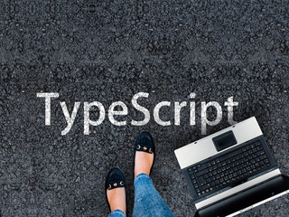 TypeScript Programming Language. Legs in sneakers standing next to laptop and word TypeScript
