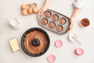 Woman with uncooked cupcakes in kitchen