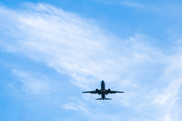 A passenger plane lands on a blue sky background on a warm summer day