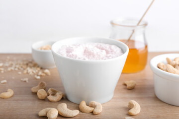 Bowl of sour cream with cashew nuts on wooden background