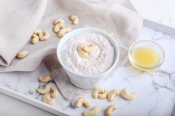 Bowl of sour cream with cashew nuts on light background