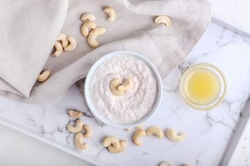 Bowl of sour cream with cashew nuts on light background