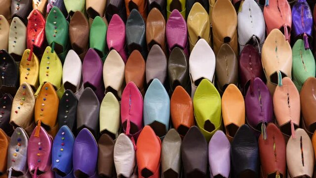 Authentic colorful Moroccan slippers (babouches), displayed on a wall, in the medina of Marrakech (Marrakesh), Morocco. Camera movement from left to right.