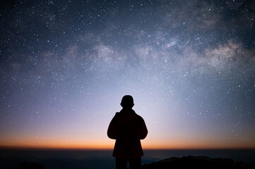 Silhouette of young traveler and backpacker standing and watched the star and milky way alone on...