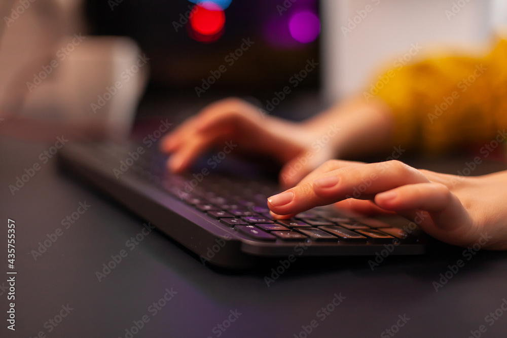 Wall mural Close-up on hands of woman gamer playing video game using keyboard. Virtual championship in cyberspace, esports player performing on pc during gaming tournament using technology network wireless.