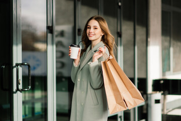 Fototapeta premium Portrait of a cheerful young lady holding shopping bags outdoor