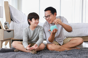 Asian father is teaching his son the saving lesson for investment in education and future planning with copy space
