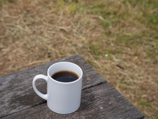 Fototapeta na wymiar 公園のテーブルの上に置かれた温かいコーヒー。マグカップに入ったブラックコーヒー。