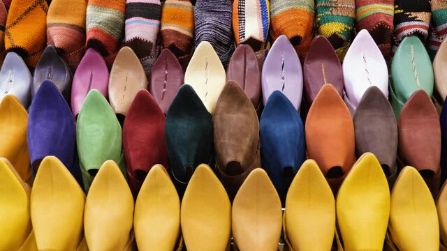 Authentic colorful Moroccan slippers (babouches), displayed on a wall, in the Medina of Marrakech (Marrakesh), Morocco. Camera movement zooming out. Yellow babouches made in Fes (Fez), woven bachouche