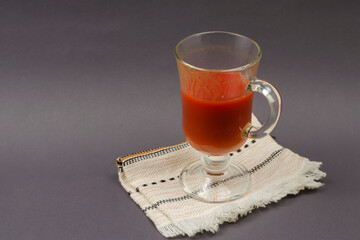A half goblet of tomato juice on a gray background. The glass st