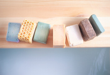 Handmade beautiful bars of organic soap displayed beside a luxurious hot bath.