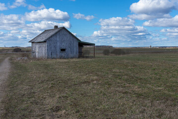 Obraz premium An old abandoned small wooden house in the fields sky clouds, barn or scary concept.