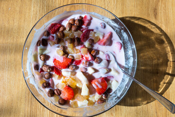 Healthy breakfast yogurt bowl,banana,hazelnuts, strawberries,oranges,apple dried fruit on a table top view.Indoors shot.