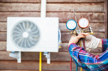 The technician is checking the air conditioner, measuring tools, refilling the old wooden house air...
